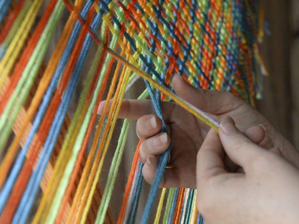 IHEA student creating a shawl on a triangle loom